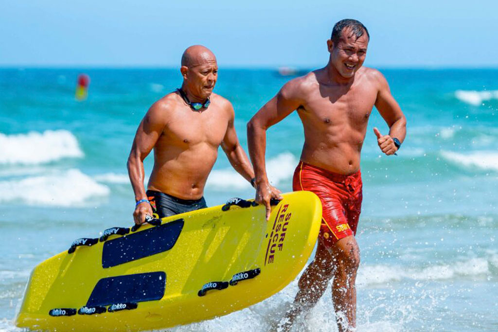 Two lifesavers carrying a rescue board from the sea